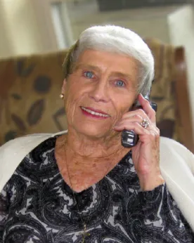 A woman with white hair talking on the phone.