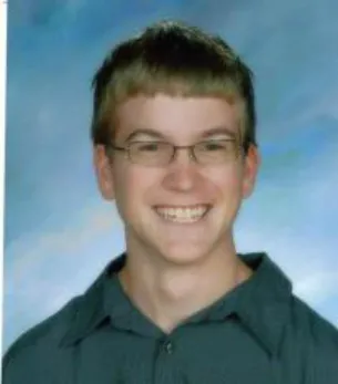 A young man with glasses smiling for the camera.