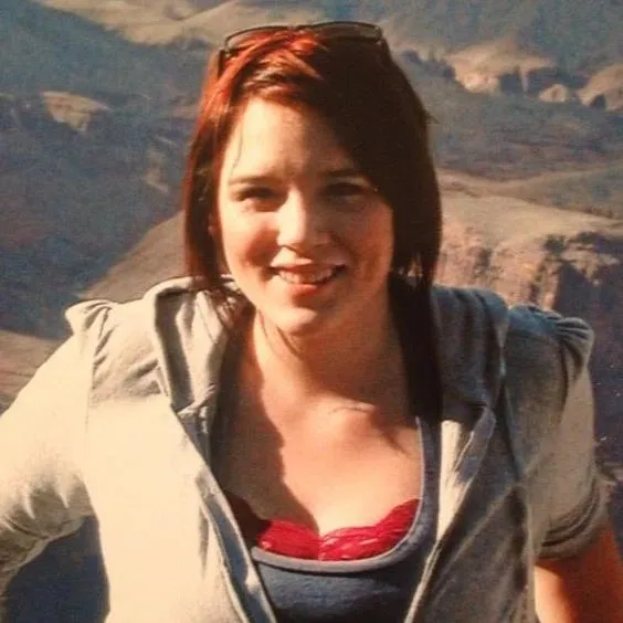 A woman standing in front of a mountain range.