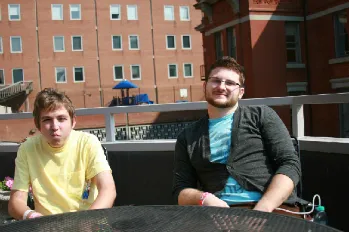 Two men sitting on a table outside of a building.