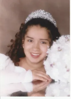 A young girl in a tiara and white dress.