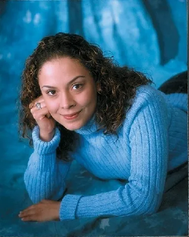 A woman in blue sweater posing for the camera.