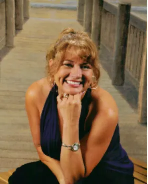 A woman smiling for the camera while sitting on steps.