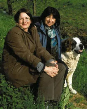 Two women and a dog sitting on the grass.