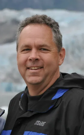 A man with gray hair and blue backpack.