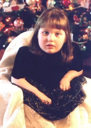 A young girl sitting in front of christmas tree.