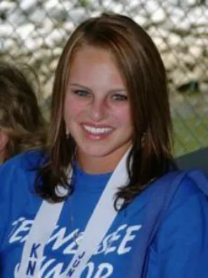 A woman in blue and white shirt smiling.