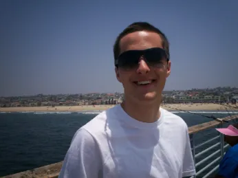 A man wearing sunglasses standing on top of a pier.