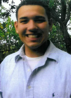 A man smiling for the camera in front of trees.