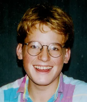 A young man with glasses smiling for the camera.