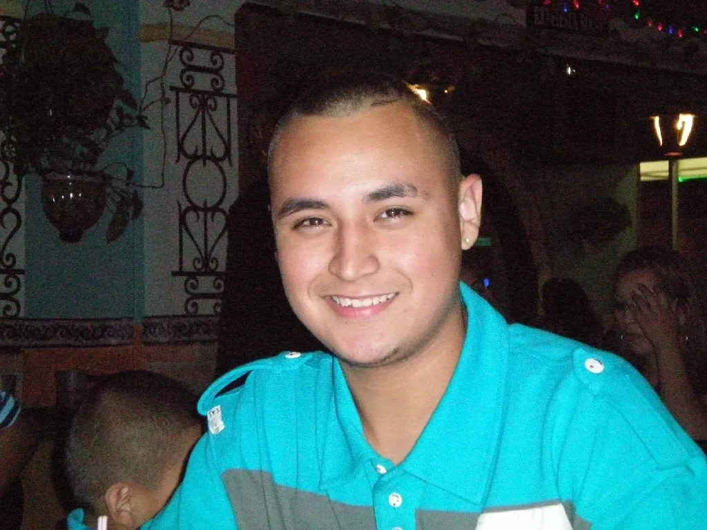 A man with a shaved head and blue shirt.