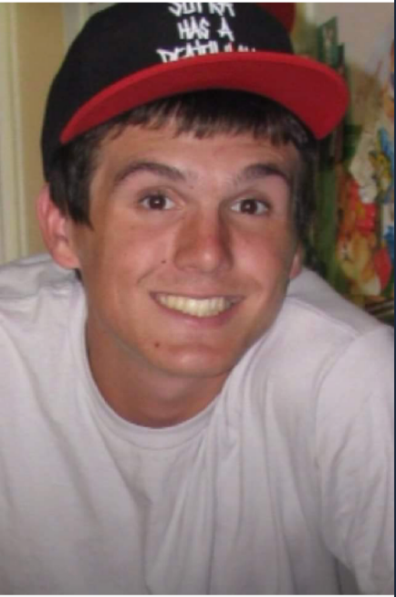 A young man wearing a red hat and smiling.