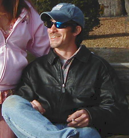 A man sitting on the ground wearing sunglasses.