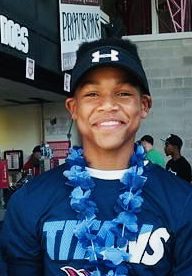 A young man wearing a baseball cap and necklace.