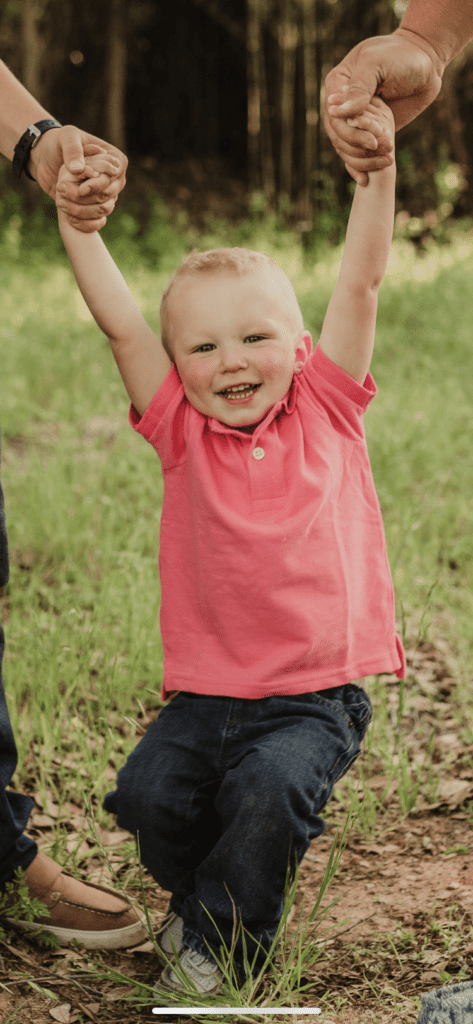 A young child is holding his hands up in the air.