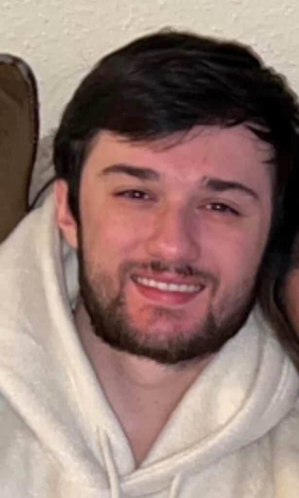 A man with beard and white shirt smiling for the camera.