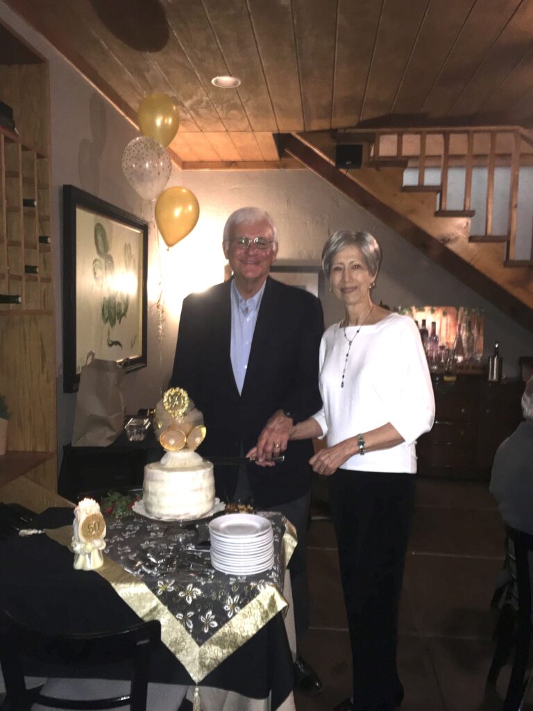 A man and woman standing in front of a cake.