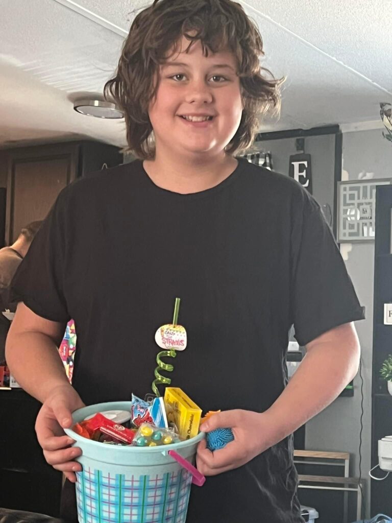 Smiling young person holding a bowl of candy indoors.