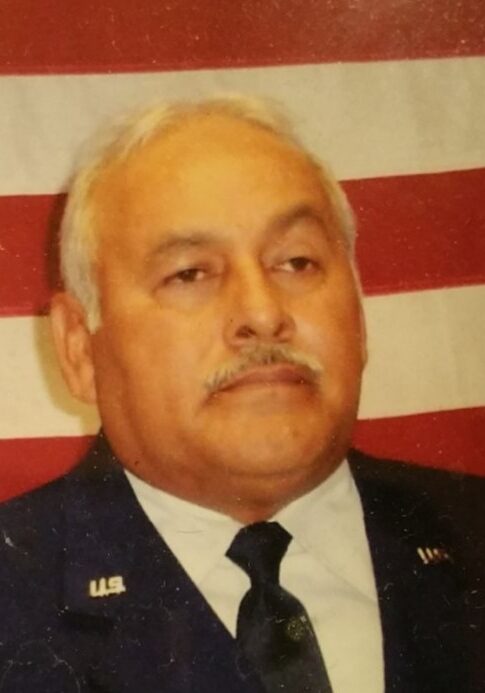 A man in military uniform sitting in front of an american flag.