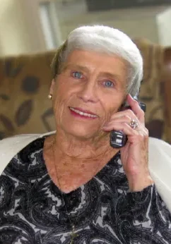 A woman with white hair talking on the phone.