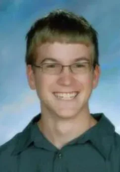 A young man with glasses smiling for the camera.