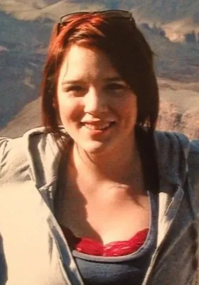 A woman standing in front of a mountain range.