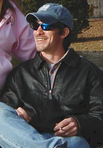Brady.sunglasses A man sitting on the ground wearing sunglasses.