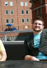 Two men sitting on a table outside of a building.