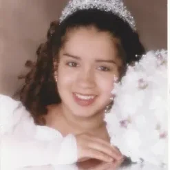 A young girl in a tiara and white dress.