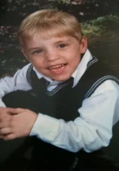 A young boy wearing a vest and tie.