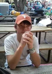 A man sitting at a table with his hands in his mouth.