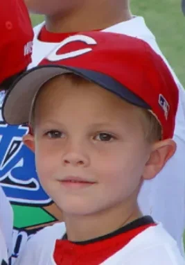 A young boy wearing a baseball uniform and hat.