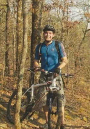 A man riding a bike through the woods.