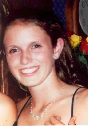 A woman smiling for the camera in front of flowers.