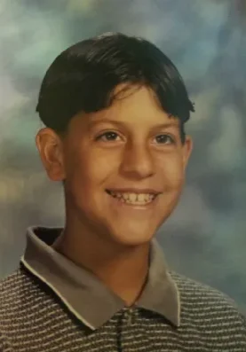 A young man with brown hair and a sweater on.