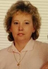 A woman with short hair and wearing a pink shirt.