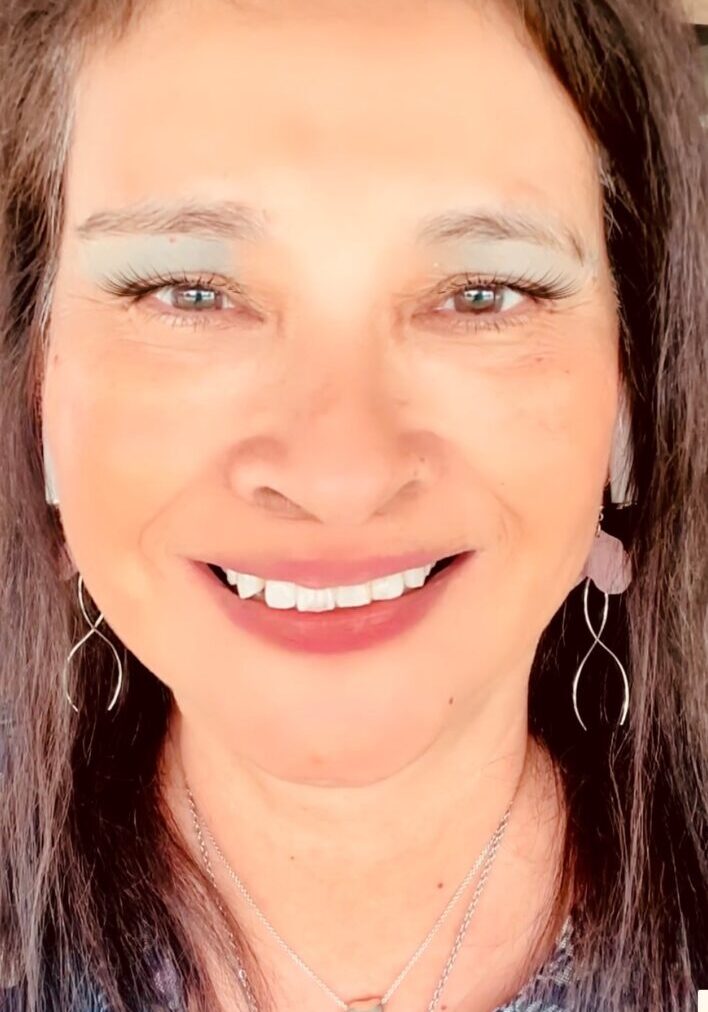 A woman with long hair and white teeth smiling.