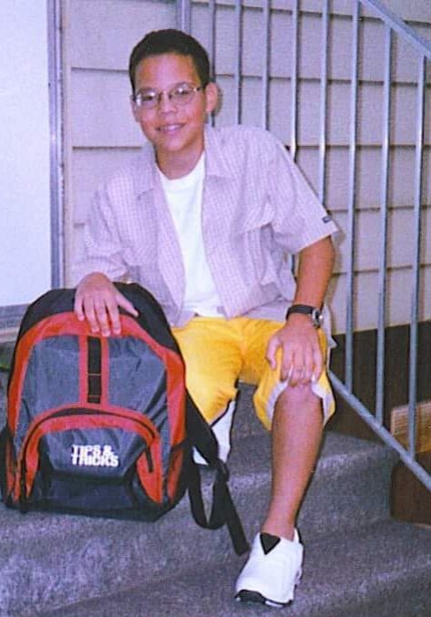 A young man sitting on steps with his backpack.