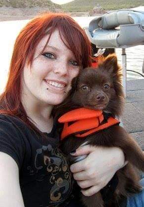 A woman holding a small dog in her arms.