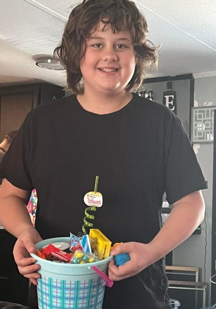 Smiling young person holding a bowl of candy indoors.