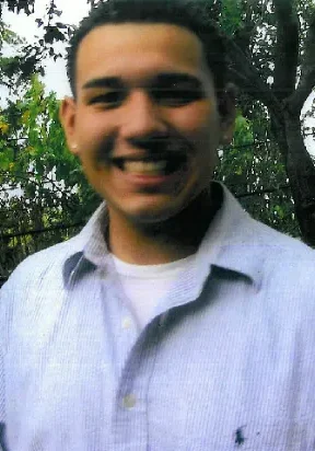 A man smiling for the camera in front of trees.