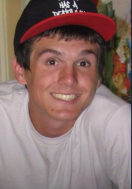 A young man wearing a red hat and smiling.