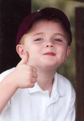 A young boy giving the thumbs up sign.