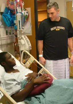 Tom Walter A man standing next to a patient in a hospital bed.