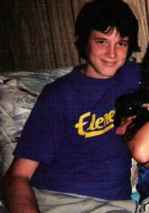 A young man sitting on top of a bed.