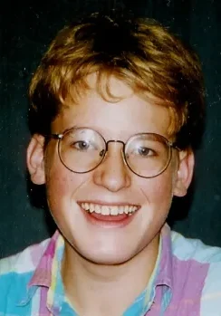 A young man with glasses smiling for the camera.